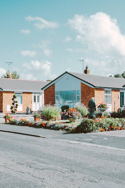 A charming small front garden in front of a white-painted house with a blue and a green door, each featuring the house number 78 above the door frames. The garden bed is edged with white concrete bord